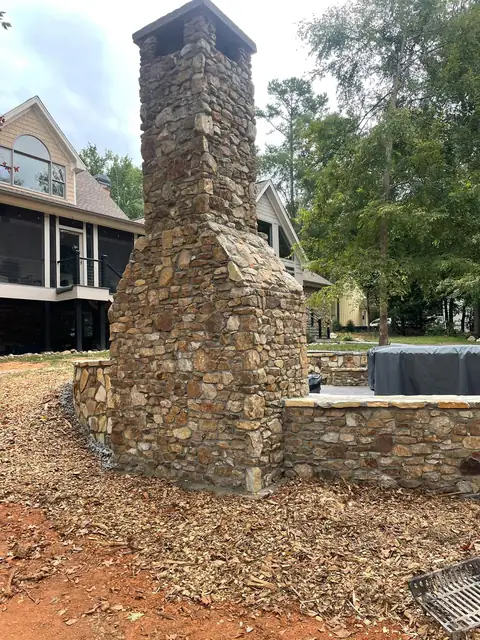 Fieldstone chimney beside a curved seating wall