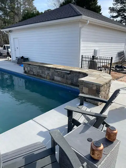 Stone-faced raised pool wall with a water feature